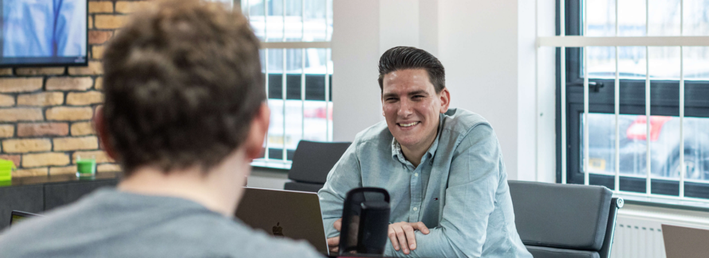 Man sat at desk smiling to co-worker